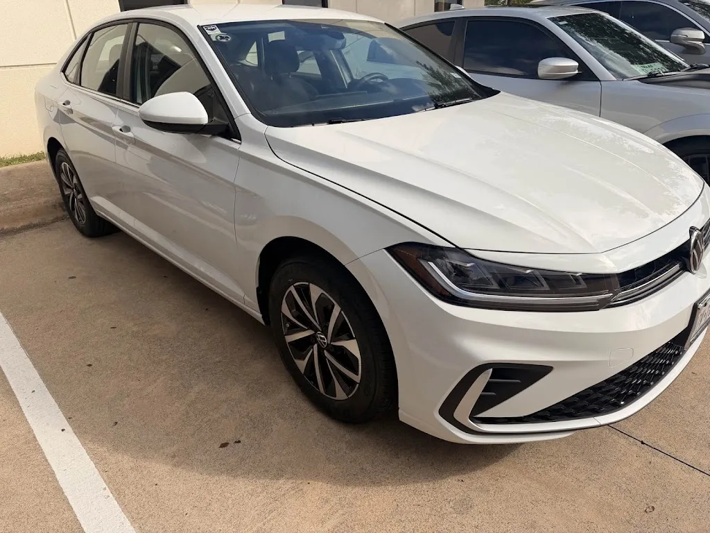 The same white Volkswagen Jetta after repair at Luxury Auto Body, front-left fender, bumper and headlight restored and refinished