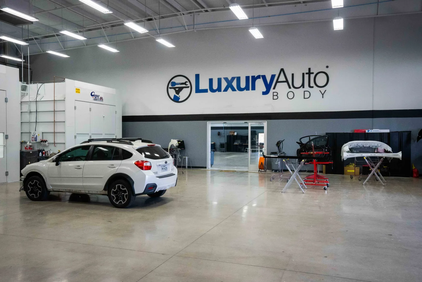 A Subaru in for repair on the Luxury Auto Body shop floor