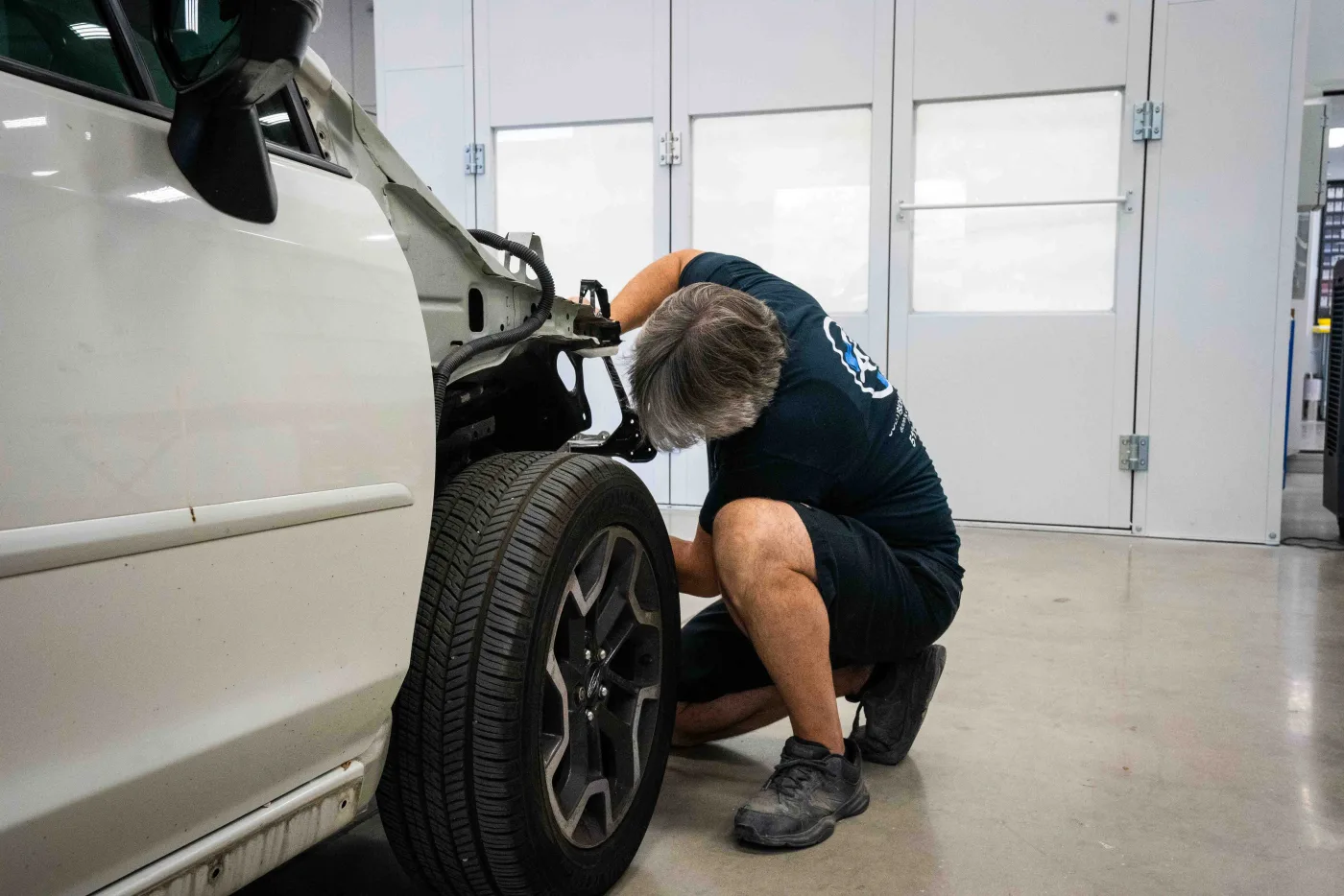 A Luxury Auto Body technician fitting a front fender on an SUV