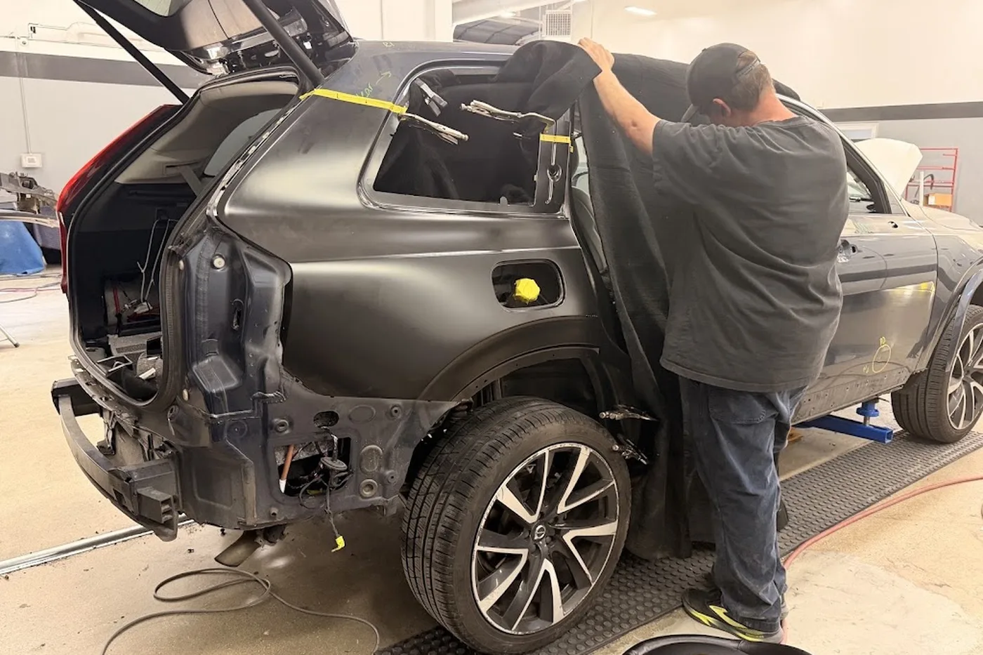 A Luxury Auto Body technician working on the stripped rear end of an SUV
